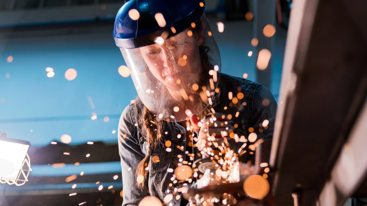 Eine Handwerkerin arbeitet mit einem Winkelschleifer in einer Werkstatt